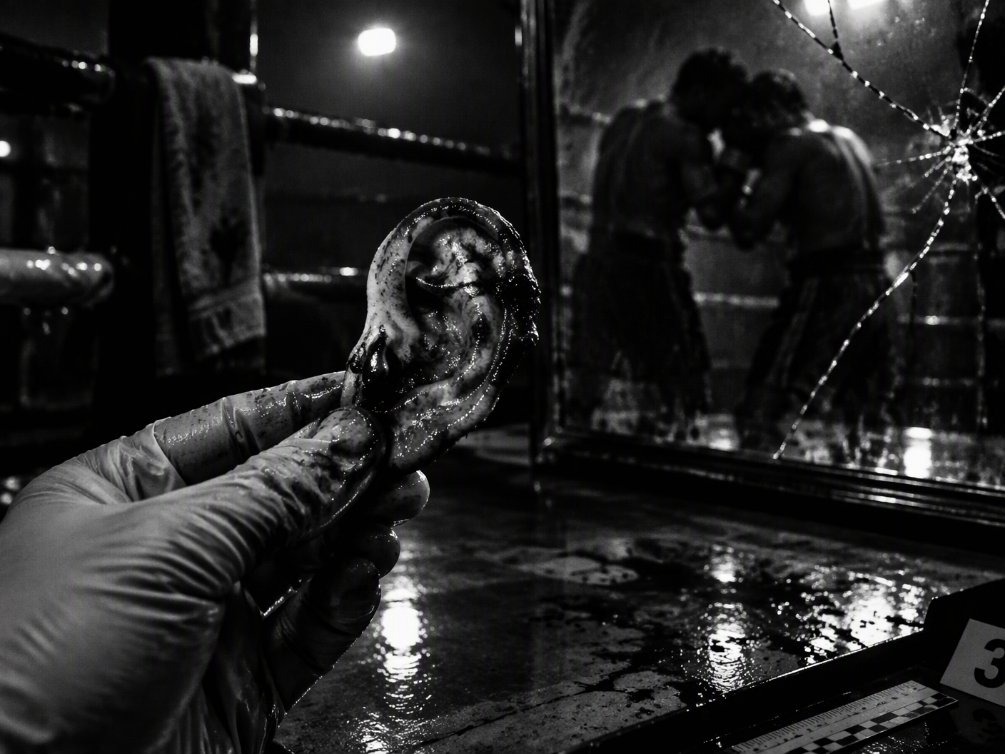 Black-and-white high-contrast image of a bloodied ear held by a gloved hand under harsh light, with shadowy, blurred silhouettes of two boxers clinched in the background reflected in a cracked mirror, evoking tension and evidence in a dimly lit boxing ring corner.